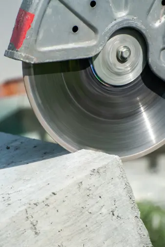 a close-up view of a circular saw slicing through a piece of concrete, showcasing the blade's sharp teeth and dust particles