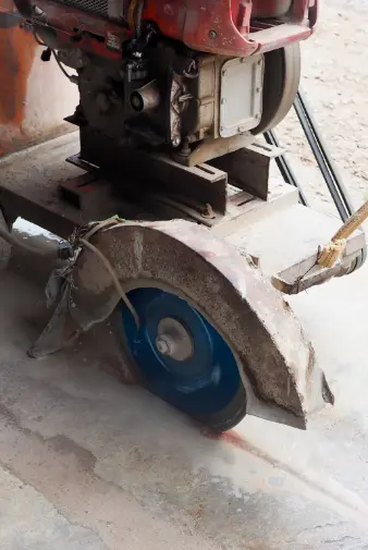a man operates a machine to cut through concrete, demonstrating precision and skill in construction work